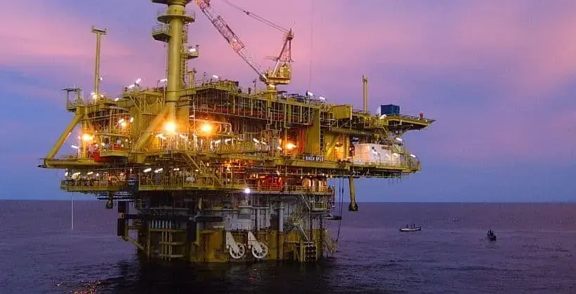 Thunder crane spar offshore oil platform with yellow lifting equipment and industrial lights at sunset